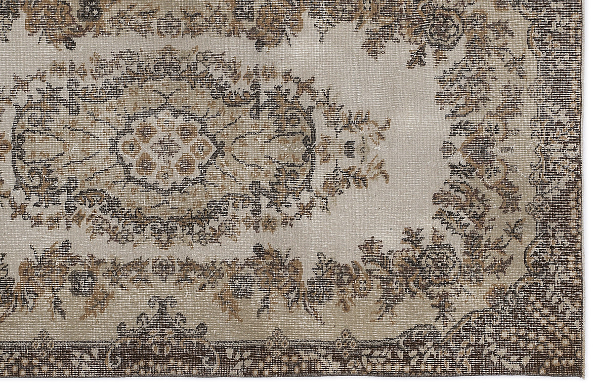 Distressed beige and brown rug with a traditional floral medallion pattern and a dark decorative border.