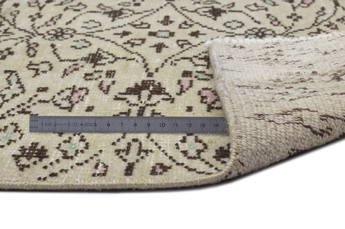 Load image 1 in gallery view. Beige rug with a brown, pink, and green floral pattern, shown with a metal ruler measuring the pile and backing.