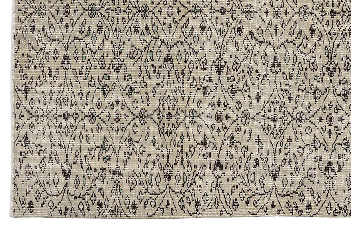Beige rug with a dark brown distressed diamond lattice pattern featuring small floral and geometric accents.