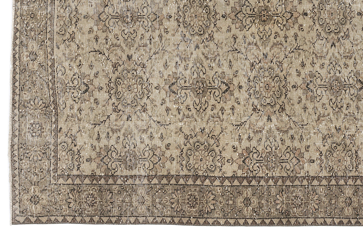 Taupe and brown distressed rug with a traditional floral medallion pattern and a geometric triangle border.