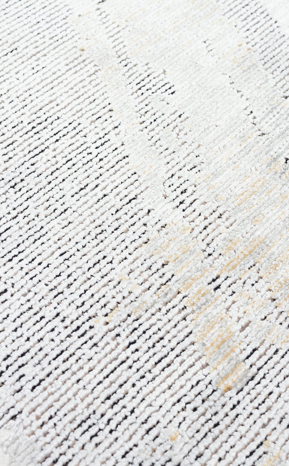 Close-up of a white and grey textured rug with subtle gold accents and a linear, distressed pattern.