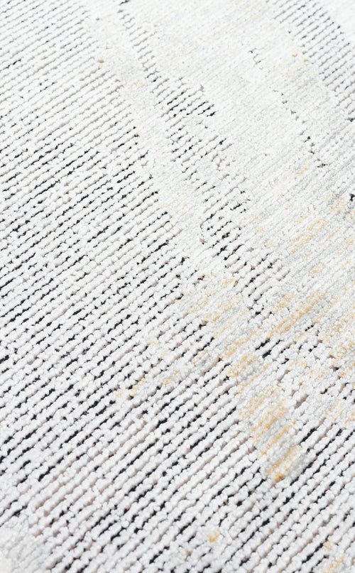 Load image 1 in gallery view. Close-up of a white and grey textured rug with subtle gold accents and a linear, distressed pattern.