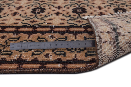 Load image 1 in gallery view. Tan and dark brown traditional patterned rug with a folded corner and a metal ruler showing pile thickness.