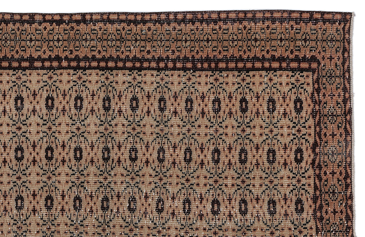 Tan and dark brown rug with a repeating geometric medallion pattern and a decorative border.