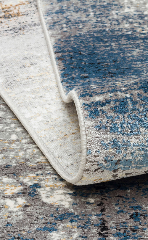 Load image 1 in gallery view. Blue, grey, and cream abstract distressed rug with a rolled edge showing a serged border.