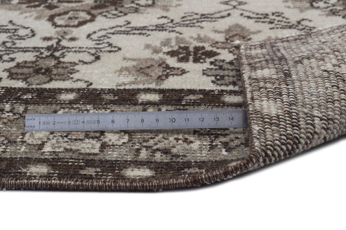 Load image 1 in gallery view. Brown and cream floral patterned rug with a folded corner showing the woven backing and a metal ruler for scale.