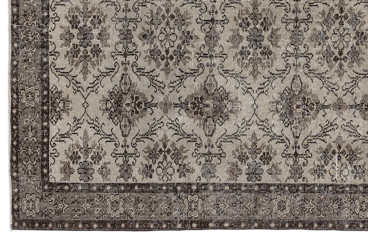 Grey and dark brown rug with a distressed traditional floral medallion pattern and a geometric border.