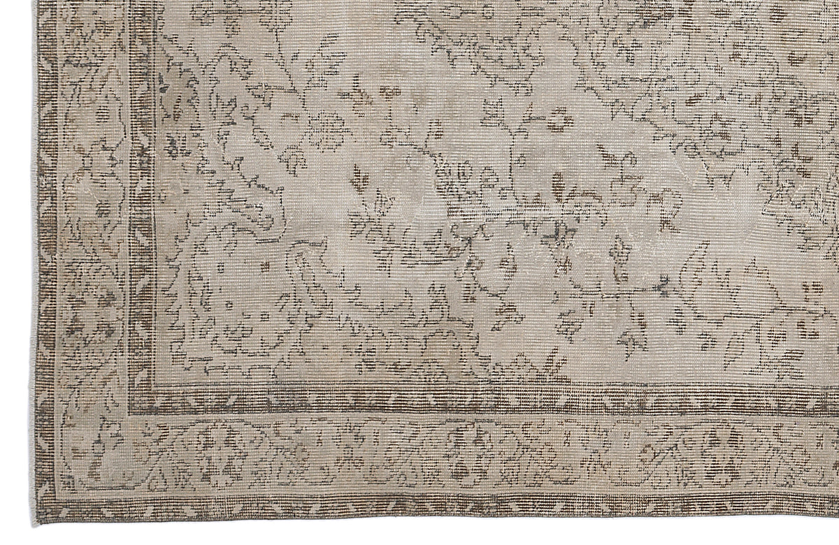 Beige and taupe vintage-style rug with a distressed floral pattern and a detailed geometric border.