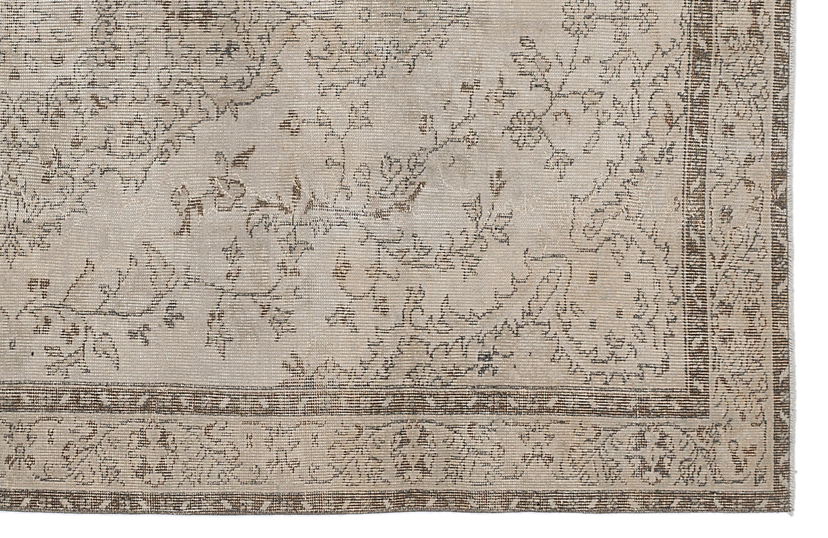 Beige and brown distressed rug with a traditional floral vine pattern and a geometric border.