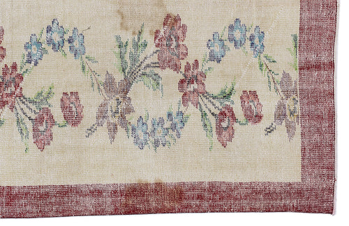 Load image 1 in gallery view. Beige rug with a red border and a floral pattern in red, blue, and green.
