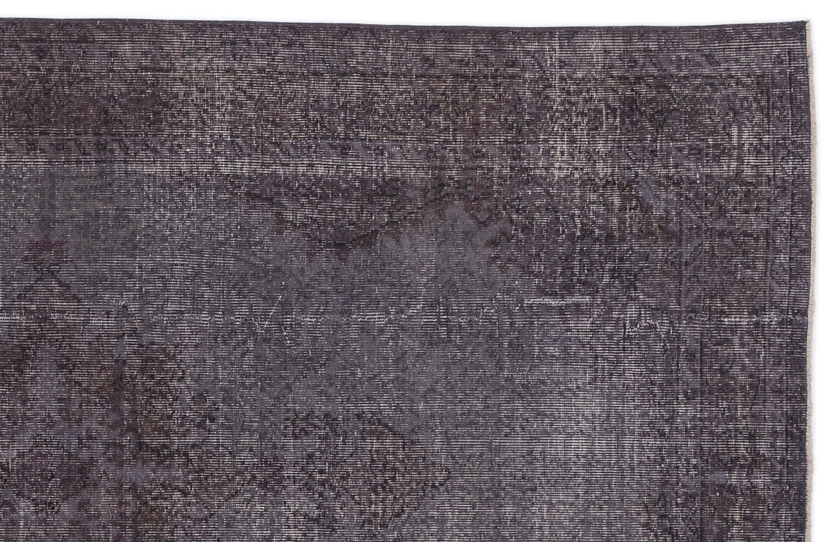 Charcoal grey rug with a distressed, faded traditional medallion pattern and a linear textured weave.