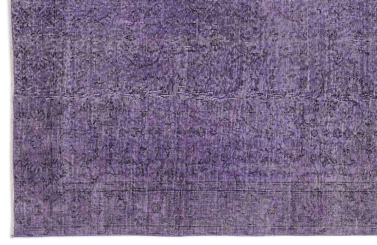 Deep purple rug with a distressed, faded traditional floral medallion pattern and a visible fringe edge.