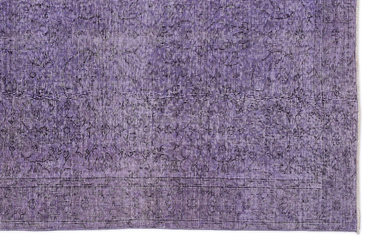 Deep purple rug with a distressed, faded floral medallion pattern and a horizontal border.