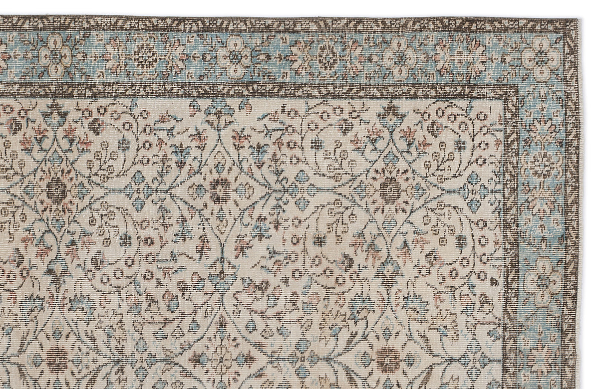 Cream rug with a blue and brown floral medallion pattern and a decorative border on a white background.