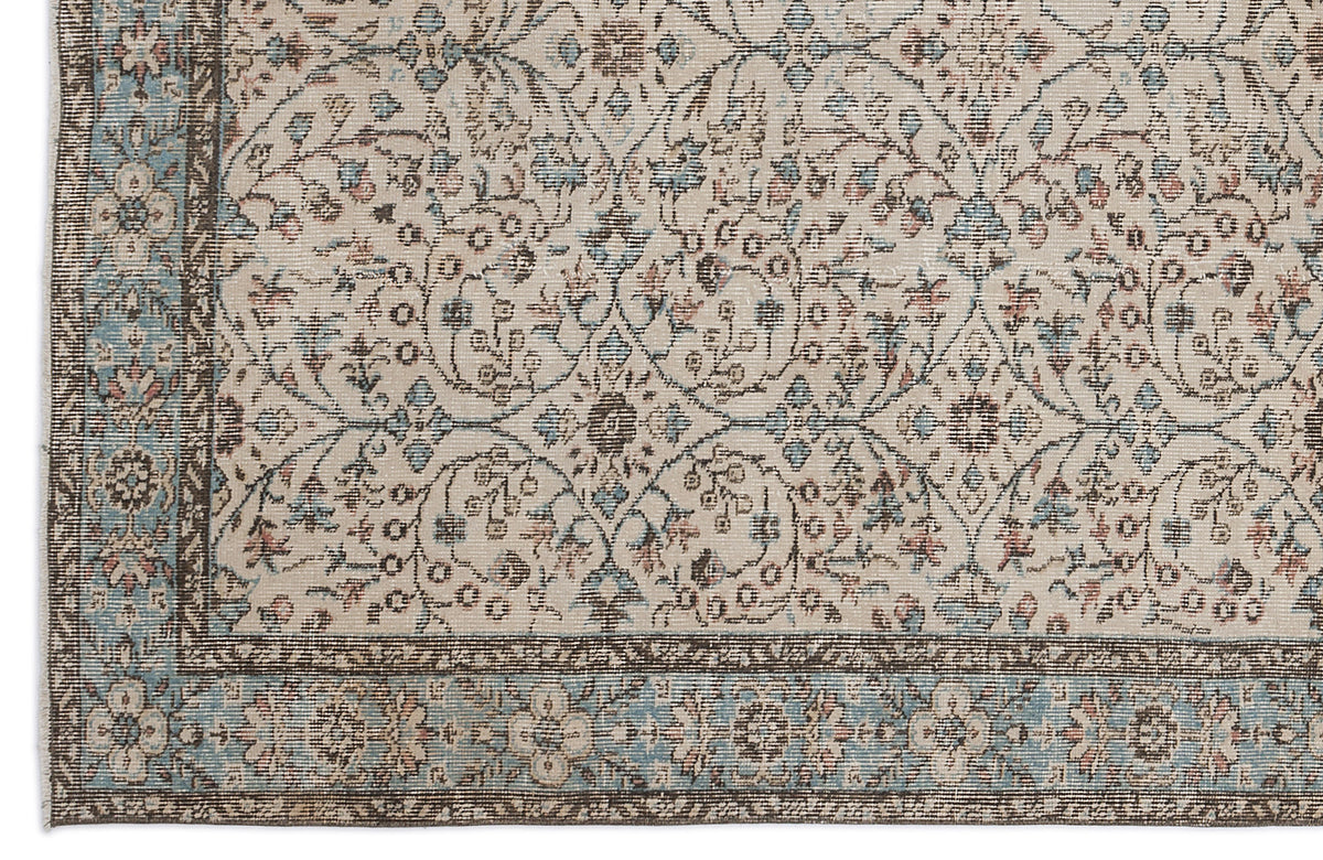 Beige rug with a faded floral medallion pattern in blue and brown, featuring a decorative border.