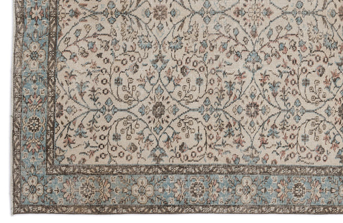 Load image 1 in gallery view. Beige rug with a faded floral medallion pattern in blue and brown, featuring a decorative border.