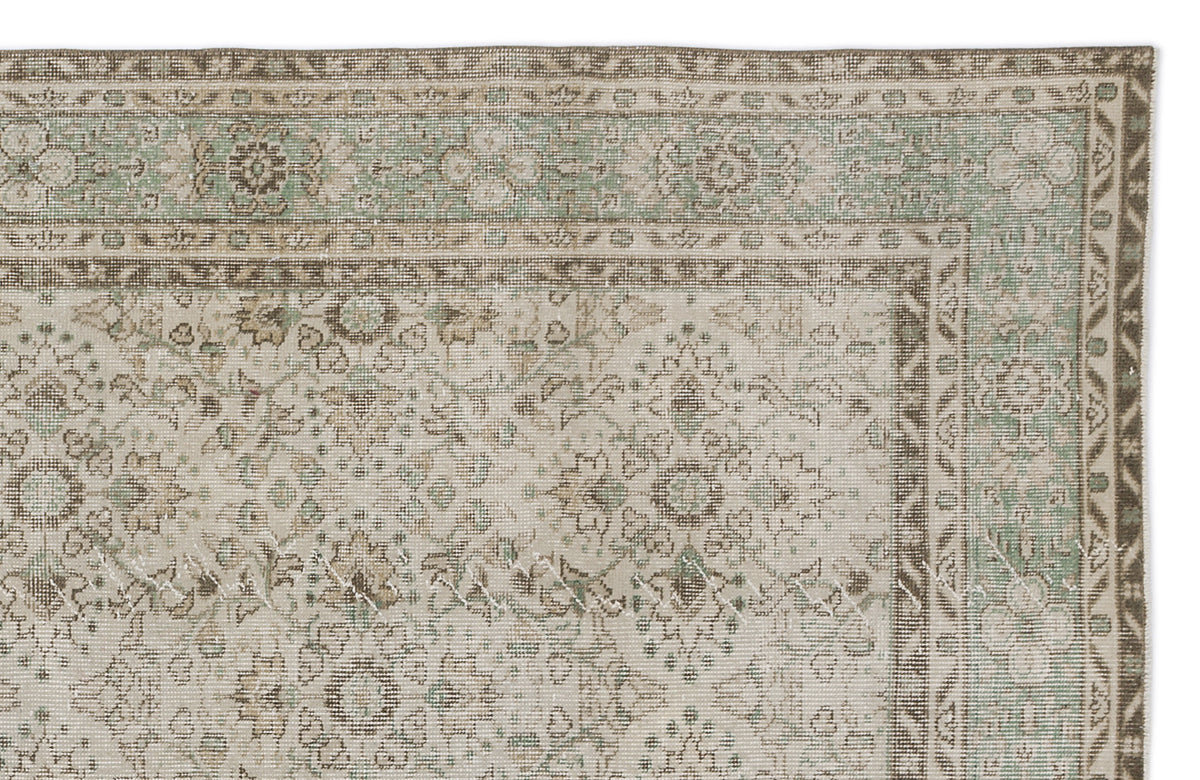 Distressed beige and sage green rug with a traditional floral medallion pattern and a geometric border.