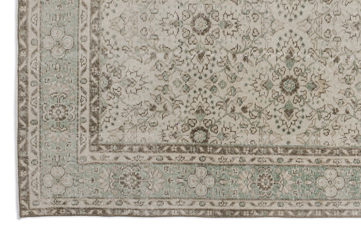 Beige and sage green traditional rug with a distressed floral medallion pattern and a detailed border.