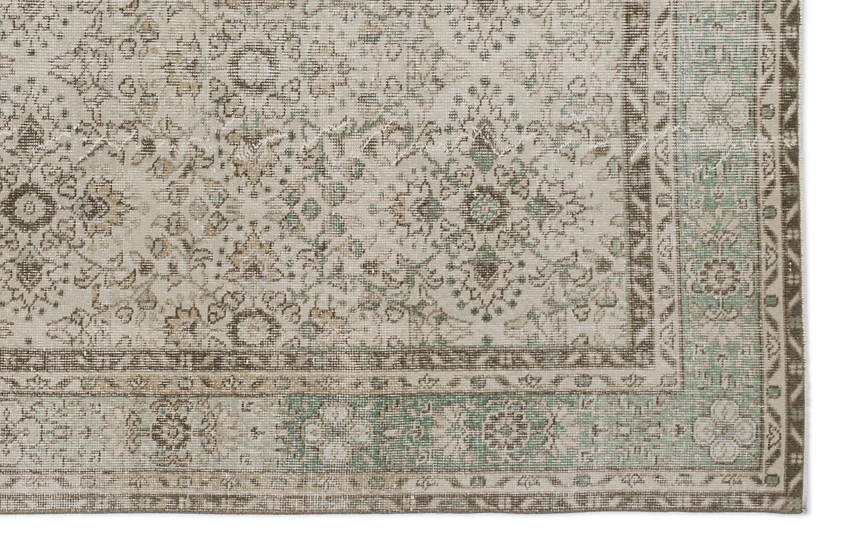 Beige and sage green vintage-style rug with a distressed floral medallion pattern and a detailed geometric border.