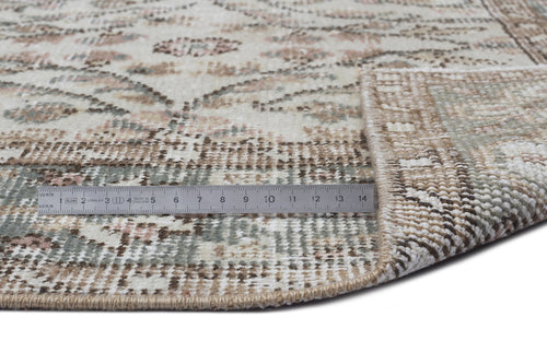 Load image 1 in gallery view. Cream, sage, and brown distressed traditional rug with a floral medallion pattern, shown with a metal ruler for scale.