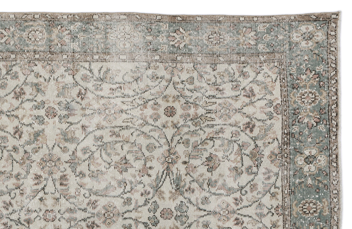 Distressed beige rug with a sage green border and faded floral medallion pattern.