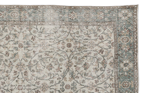 Load image 1 in gallery view. Distressed beige rug with a sage green border and faded floral medallion pattern.