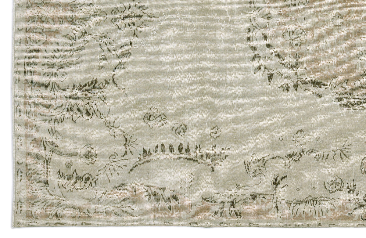 Beige and sage green distressed rug with a faded traditional floral medallion pattern.