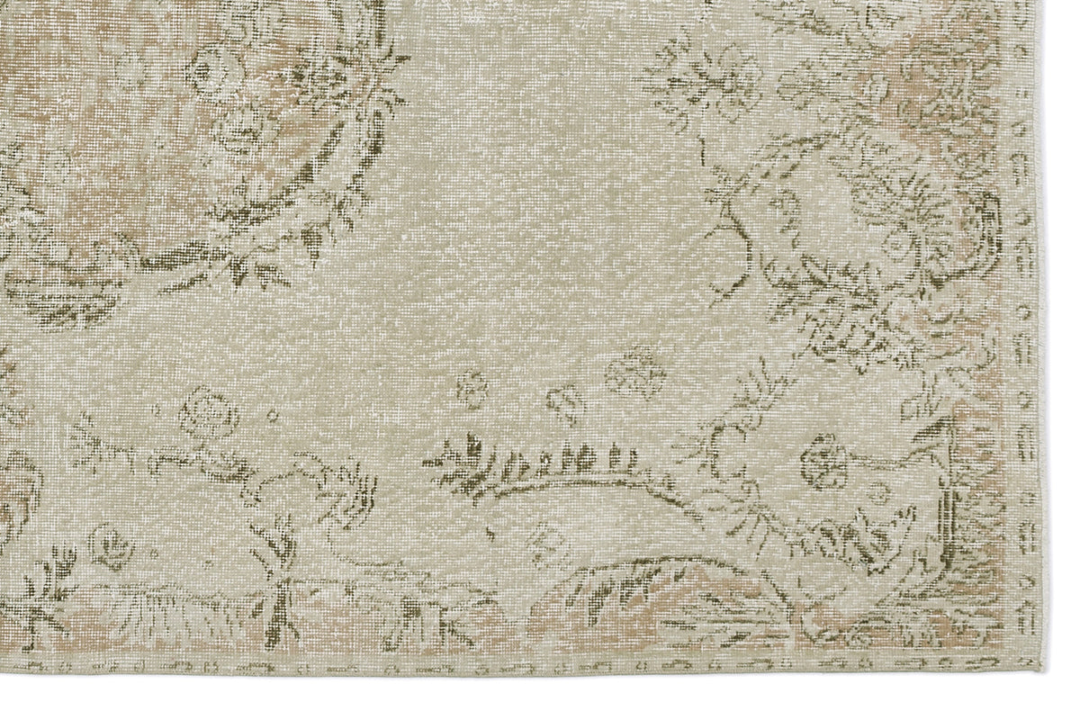 Beige and sage green distressed rug with a faded floral medallion pattern.