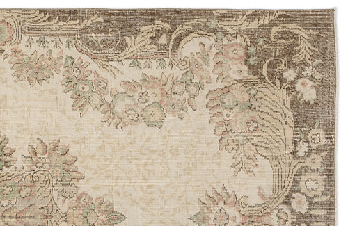 Load image 1 in gallery view. Beige rug with a dark brown border and muted floral medallion pattern in faded pink and sage green.