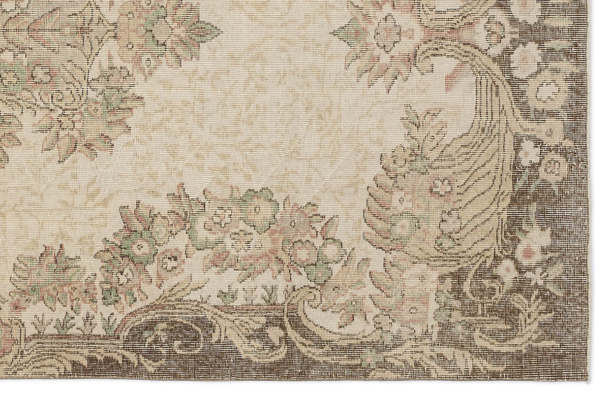 Beige rug with a dark brown border and muted floral motifs in sage green and dusty pink.