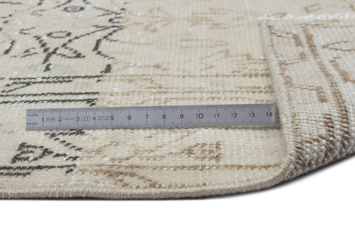 Load image 1 in gallery view. Beige and cream vintage-style rug with a faded charcoal geometric pattern, shown with a metal ruler for scale.