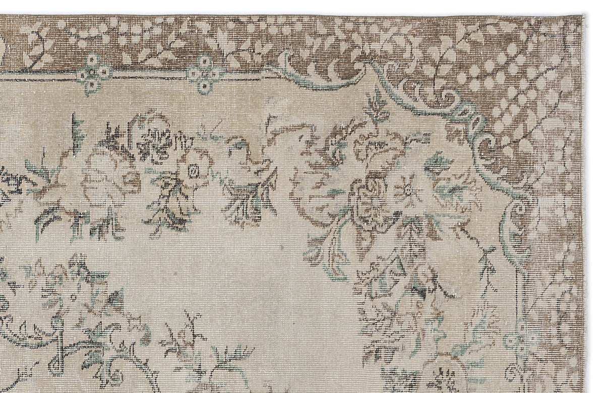 Beige and brown traditional rug with a distressed floral medallion pattern and teal accents.