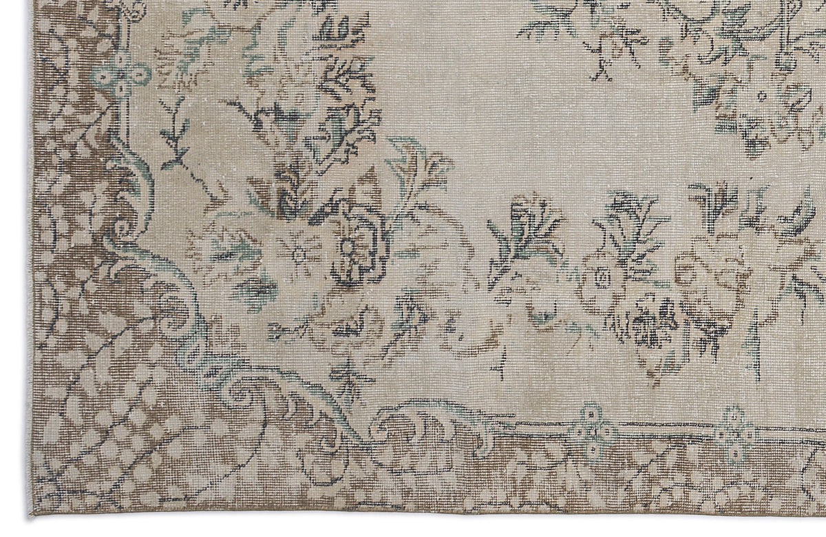 Beige and brown traditional rug with a distressed floral medallion pattern and muted teal accents.