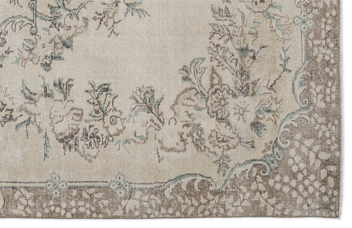 Load image 1 in gallery view. Beige rug with a distressed floral pattern in muted brown and teal, featuring a decorative border.