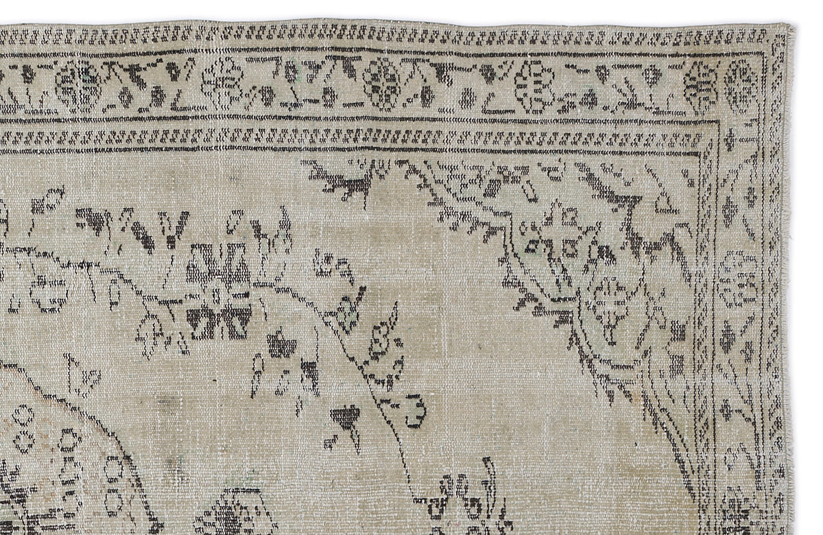 Beige and charcoal distressed rug with a traditional floral medallion border and faded botanical motifs.