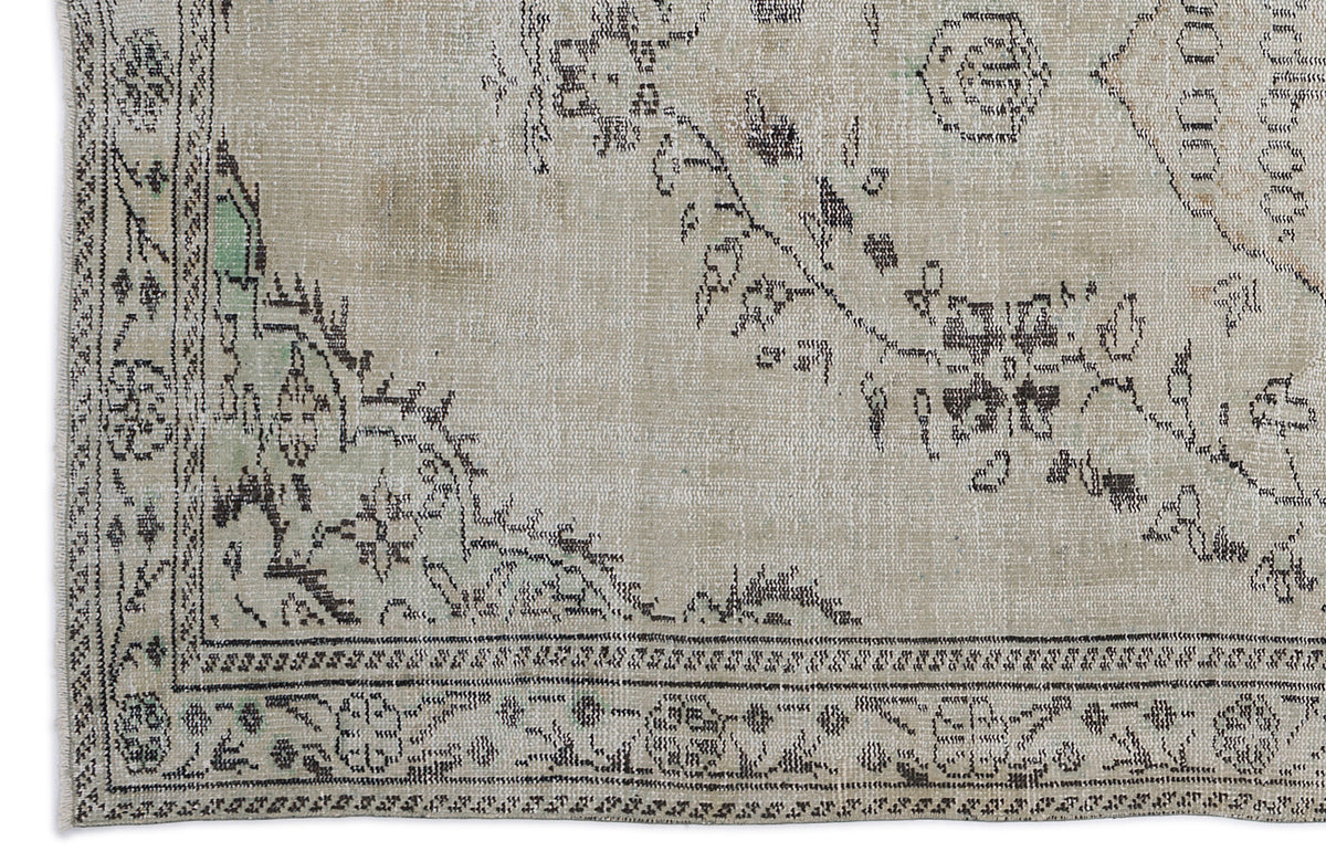 Beige vintage-style rug with a distressed black floral medallion pattern and subtle green accents.