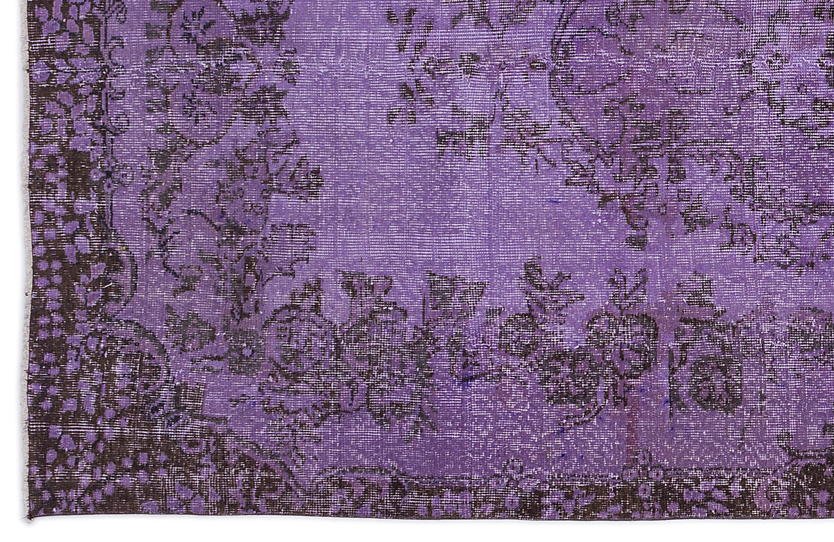 Distressed purple rug with a dark charcoal floral medallion pattern and ornate border.