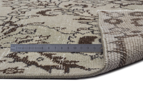 Load image 1 in gallery view. Beige and brown distressed floral pattern rug with a folded corner and a metal ruler for scale.