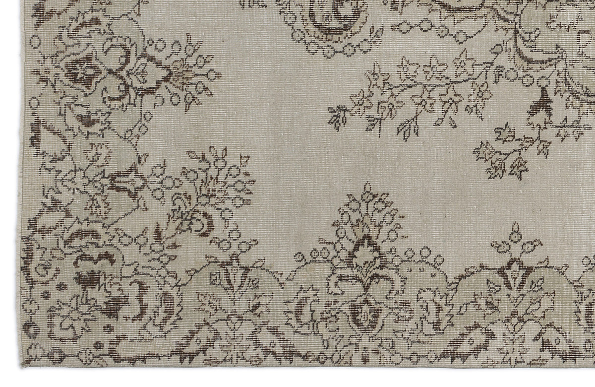 Beige rug with a dark brown distressed floral and paisley pattern.