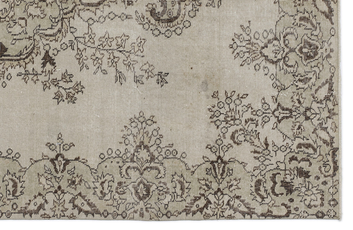 Beige rug with a dark brown distressed floral medallion pattern and a fringed edge.