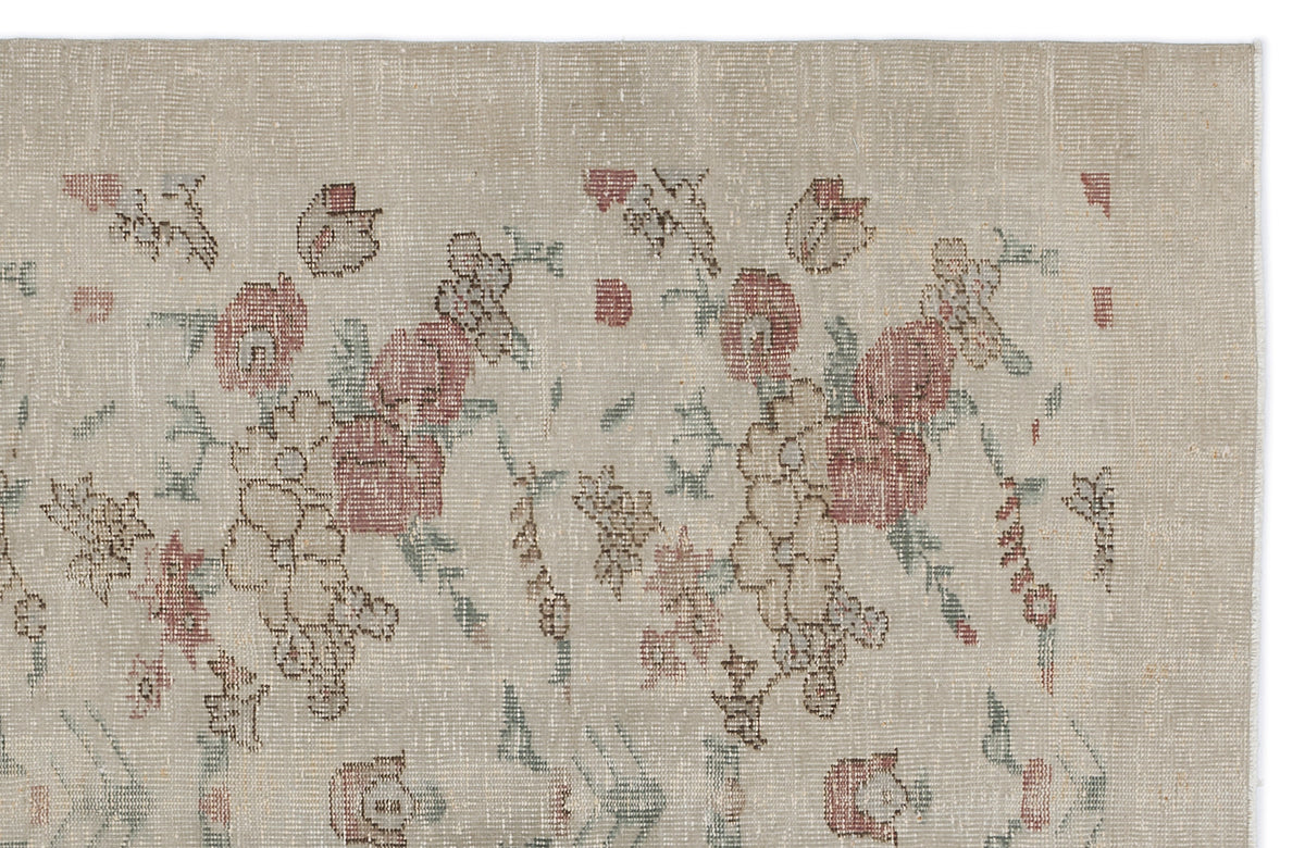 Beige vintage-style rug with a faded floral pattern in muted red, green, and brown tones.