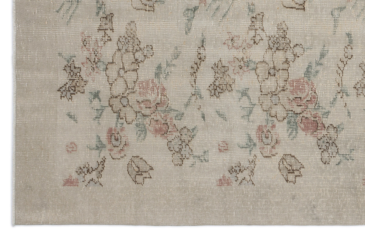 Beige rug with a distressed floral pattern in muted pink, brown, and sage green.