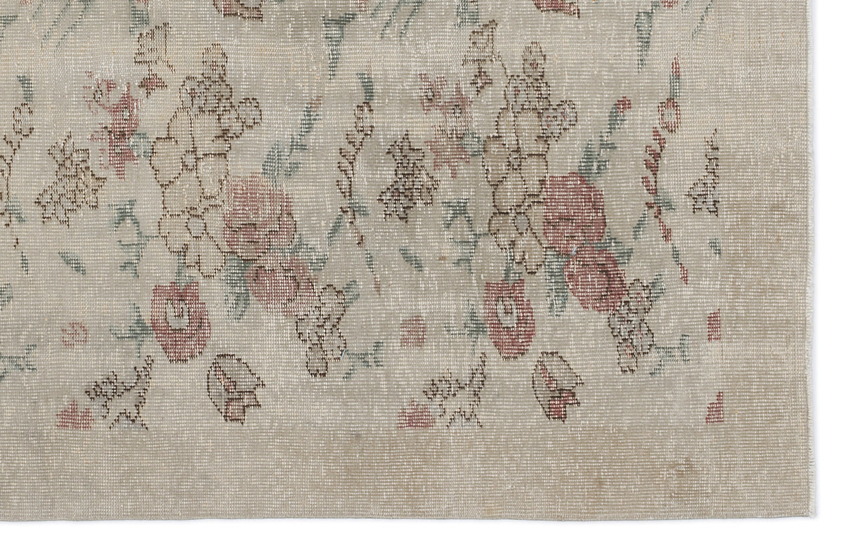 Beige rug with a distressed floral pattern in muted red and sage green.