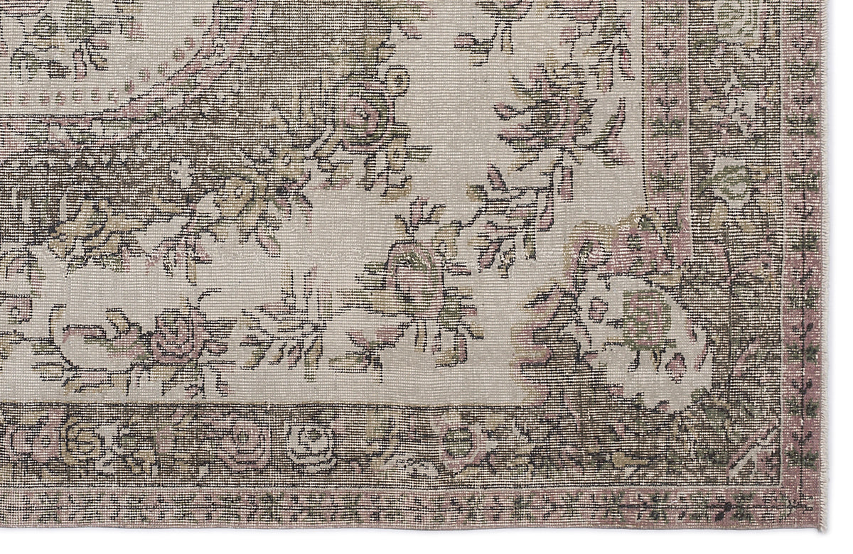 Distressed beige rug with a faded floral pattern in muted pink and olive green, featuring a decorative border.