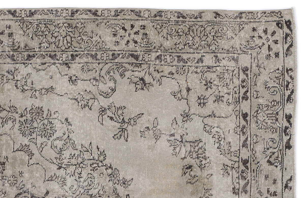 Distressed beige and charcoal grey rug with a traditional floral border and central vine motif.