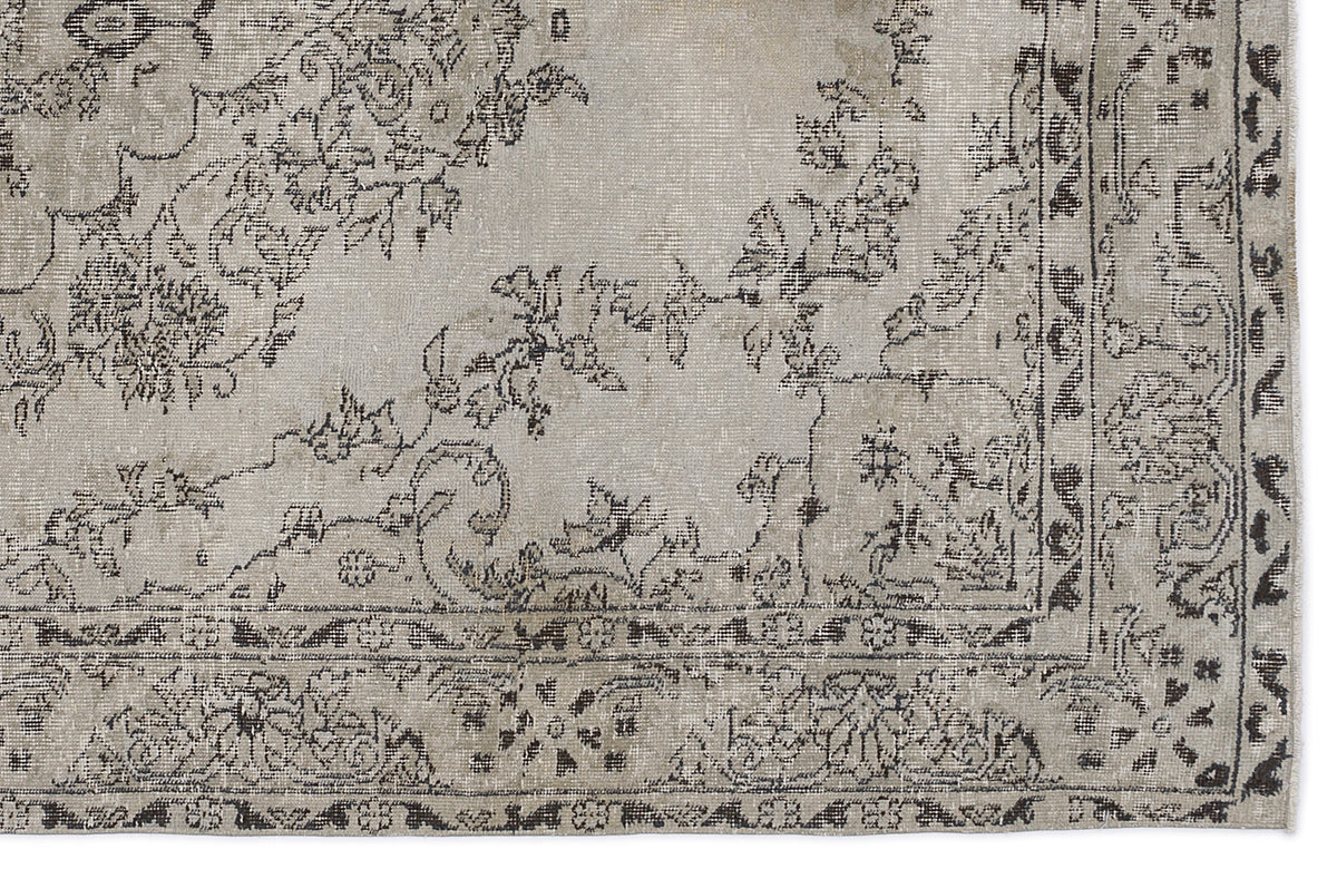 Distressed beige and charcoal grey rug with a traditional floral medallion pattern and a detailed border.