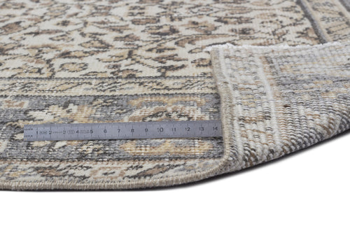 Load image 1 in gallery view. Beige and grey round rug with a distressed floral pattern, shown with a metal ruler for scale on a white background.