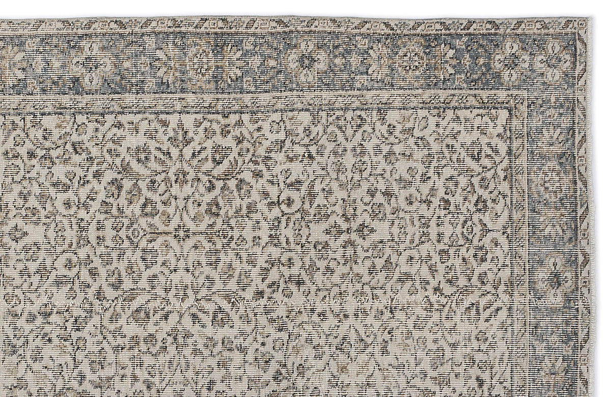Grey and beige vintage-style rug with a distressed floral medallion pattern and a detailed border.