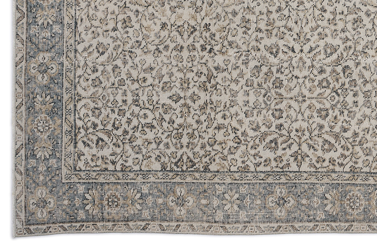 Beige and slate blue rug with a distressed traditional floral pattern and a decorative border.