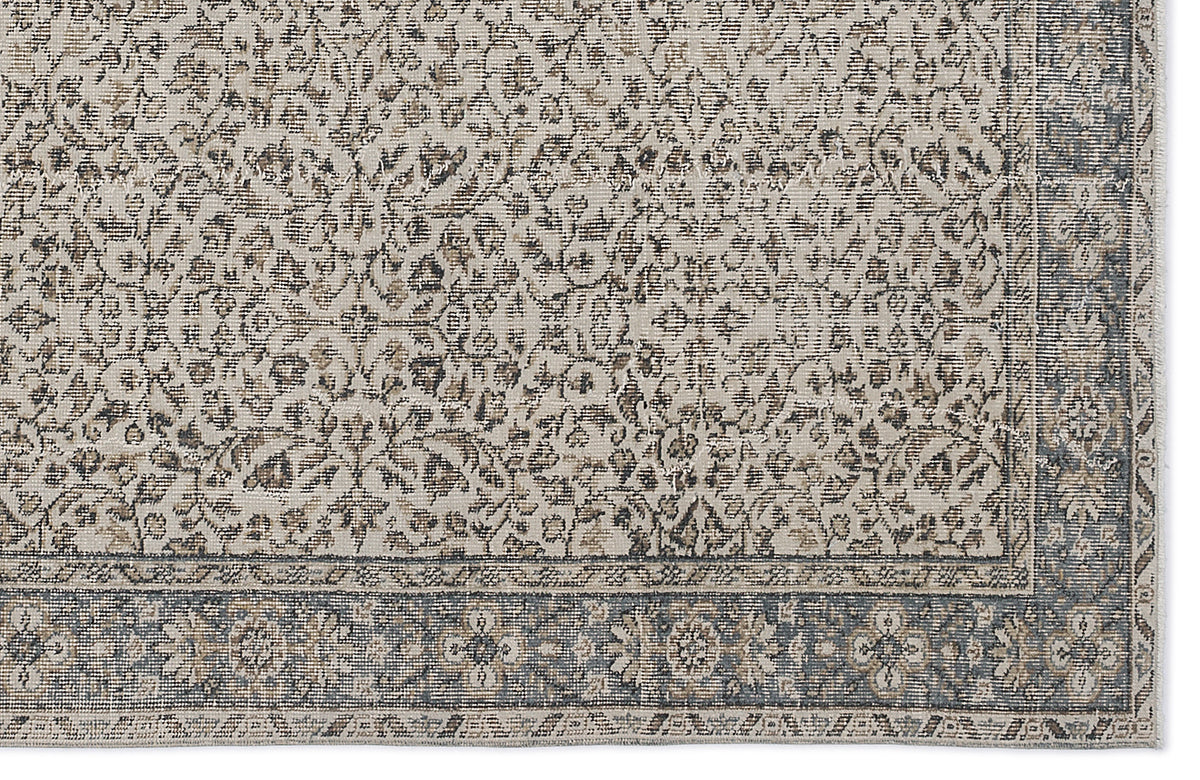 Beige and charcoal grey rug with a distressed traditional floral pattern and a wide decorative border.